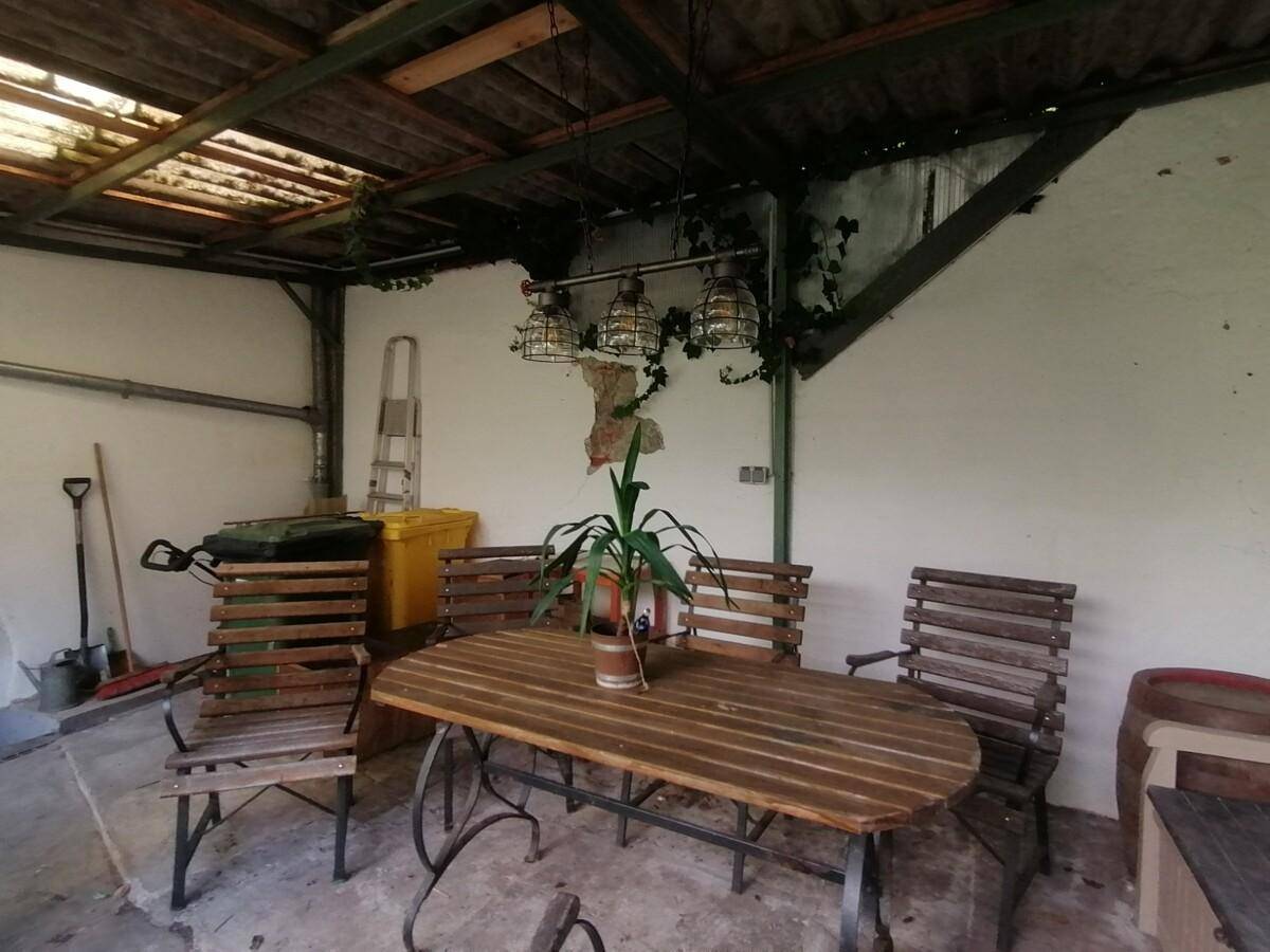 Überdachter Außenbereich mit Holztisch und Stühlen, ideal für Mahlzeiten im Freien.