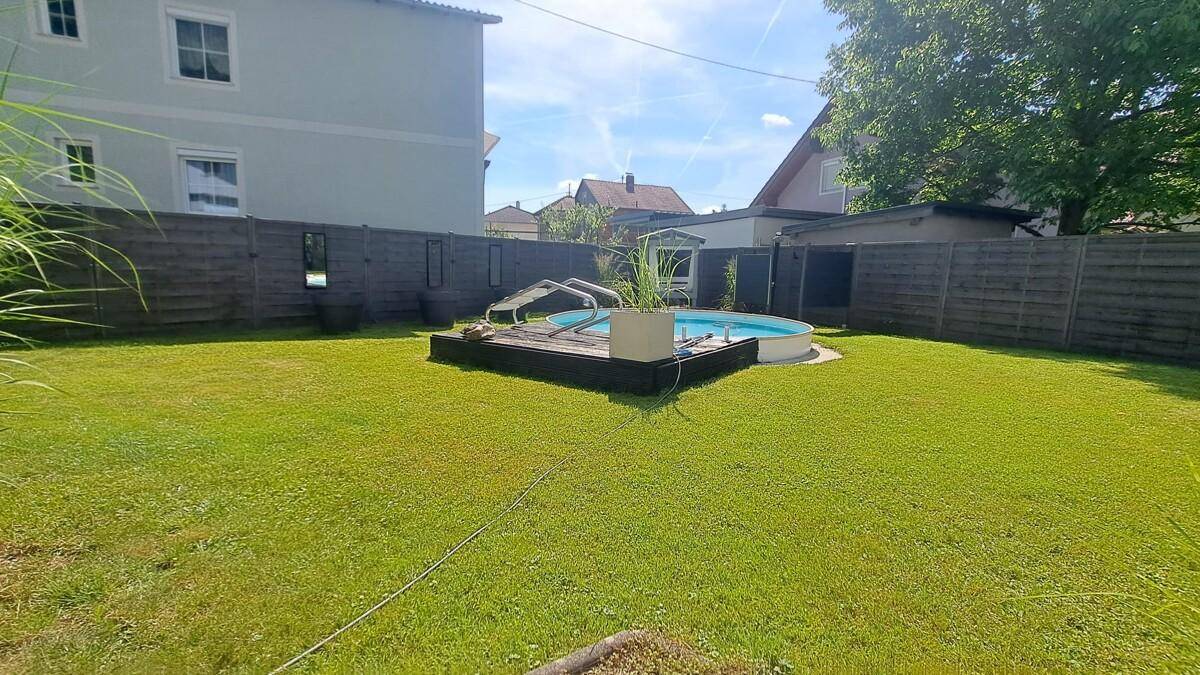 Weitläufiger Garten mit Rasenfläche und zentral platziertem oberirdischem Pool.