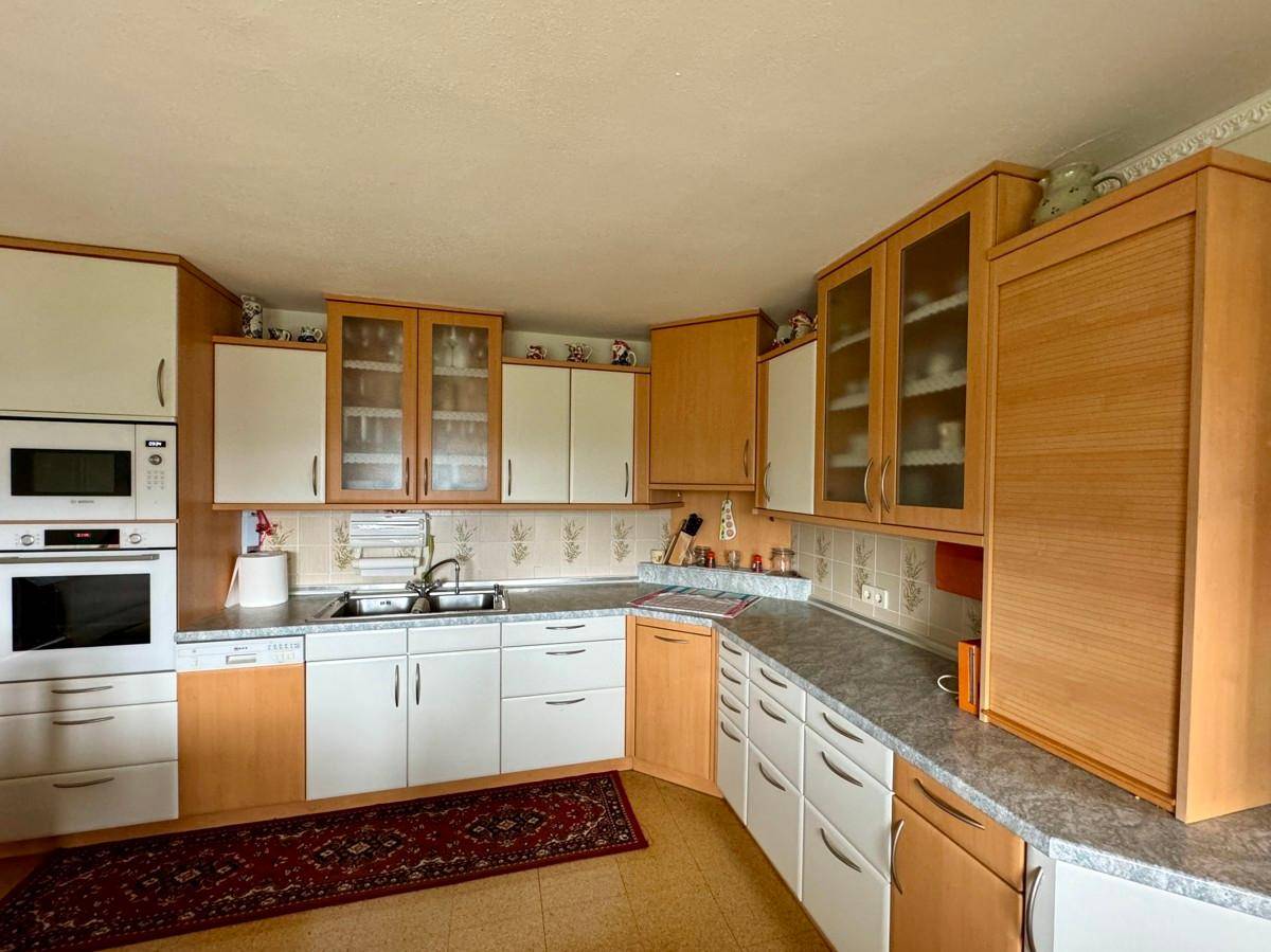 Traditionelle Küche mit Holz- und weißen Fronten, integrierten Geräten und Fliesenboden.