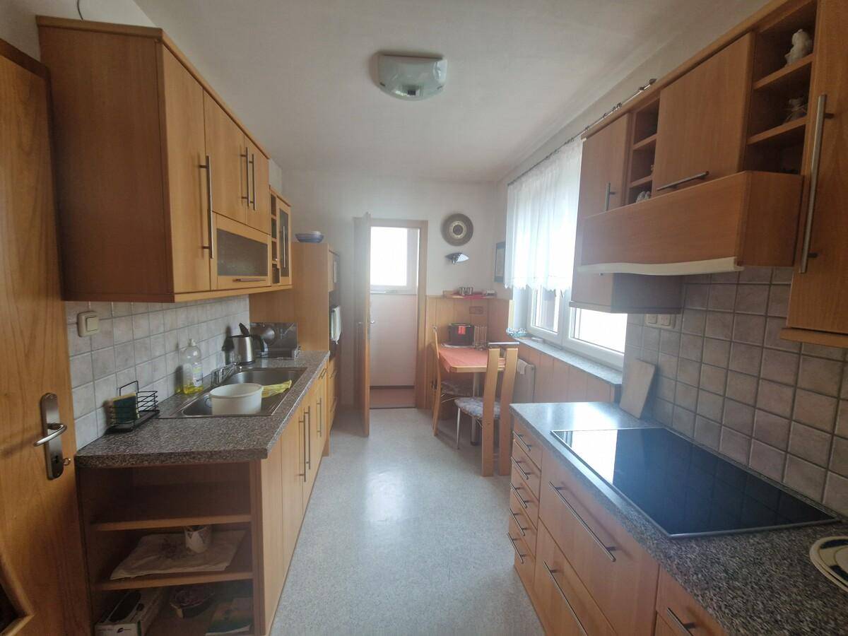 Funktionale Küche mit Holzschränken, Granitarbeitsplatte und Essbereich am Fenster.