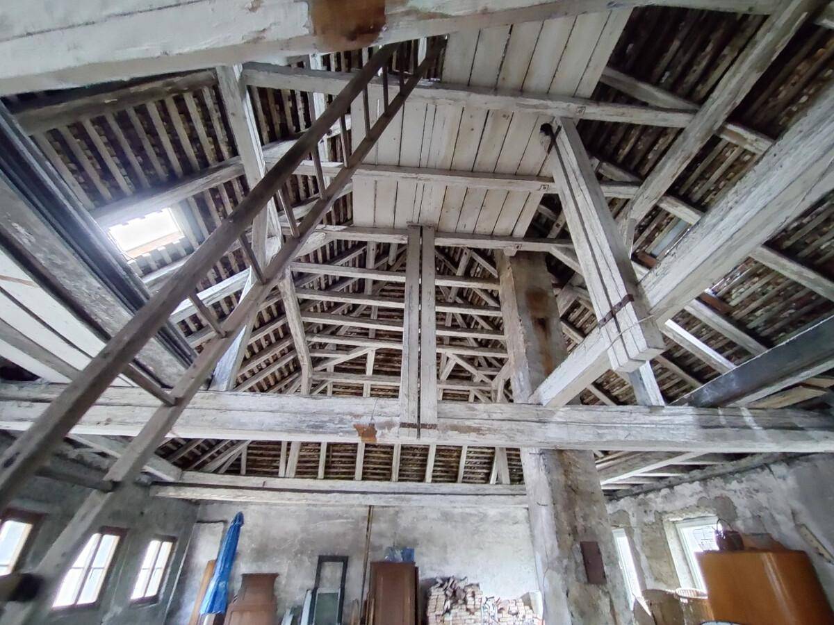 Detailansicht der beeindruckenden Holzbalkenkonstruktion des Dachstuhls mit Leiter und Oberlicht.