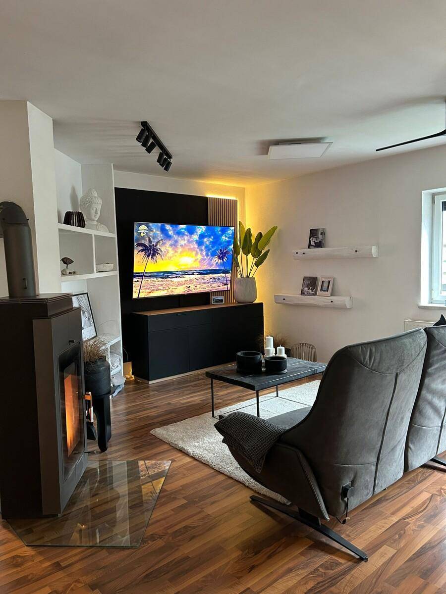 Stilvolles Wohnzimmer mit Kaminofen, bequemer Couch und modernem Unterhaltungssystem.