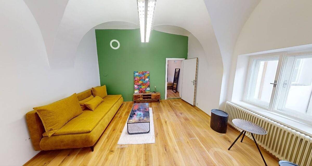 Geräumiges Wohnzimmer mit gelbem Sofa, Holzboden und grüner Akzentwand.