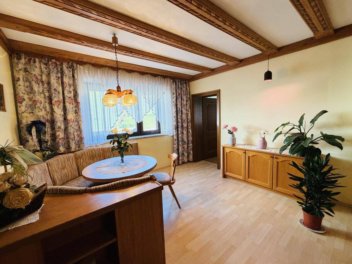 Wohnzimmer mit Holzbalkendecke, Parkettboden und traditioneller Einrichtung.