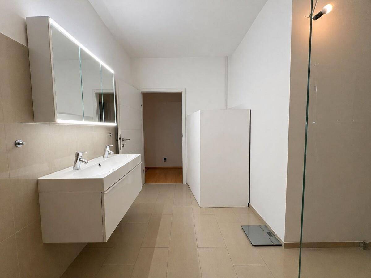 Geräumiges Badezimmer mit Doppelwaschbecken, großem Spiegelschrank und hellen Fliesen.
