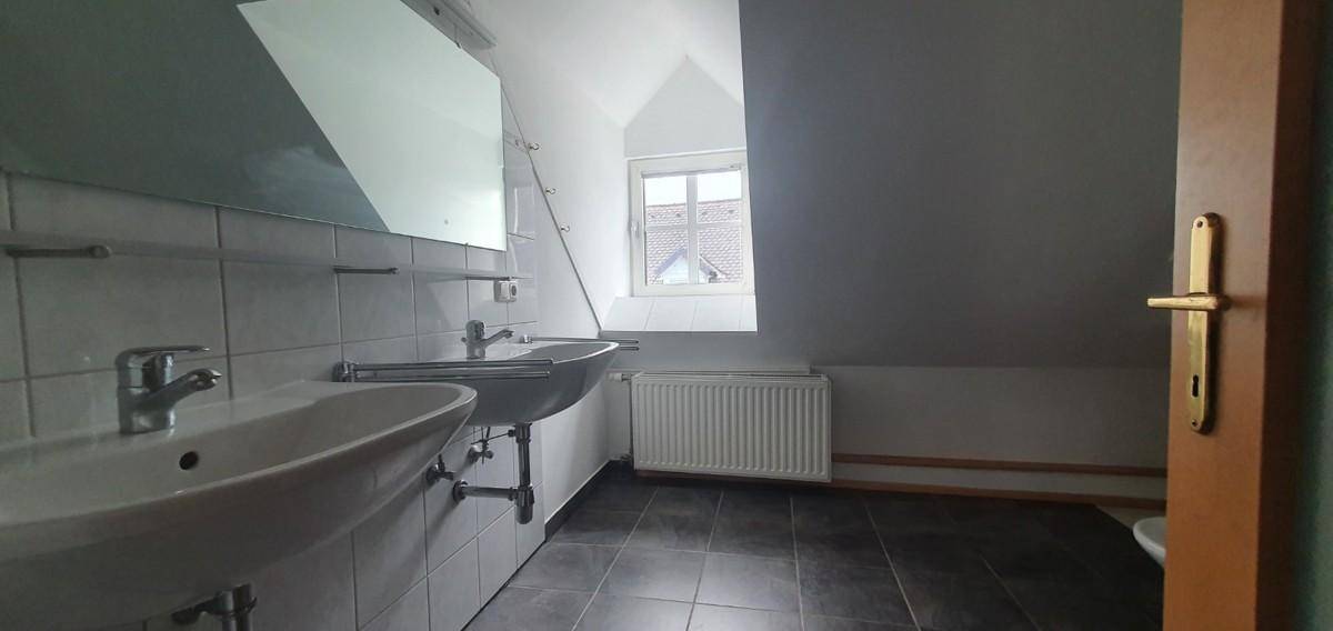 Geräumiges Badezimmer mit Doppelwaschbecken, Fliesenboden und Dachfenster.