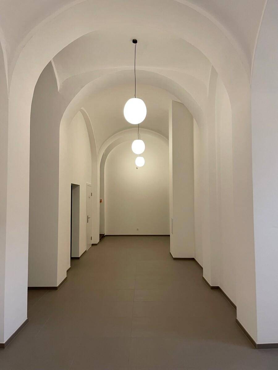 Langer, gewölbter Flur mit mehreren Türen und modernen Hängelampen.