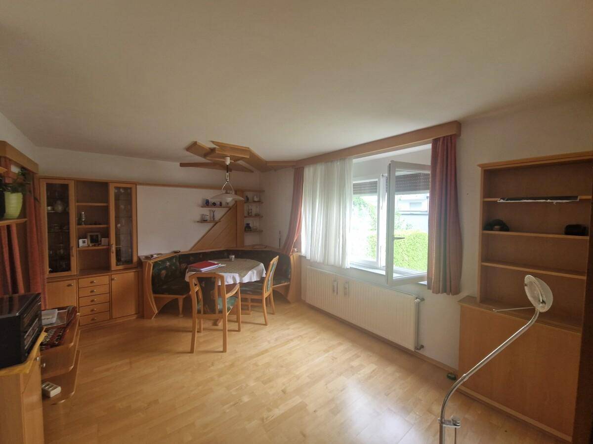 Geräumiger Wohn- und Essbereich mit Holzparkett, großem Fenster und traditionellen Möbeln.