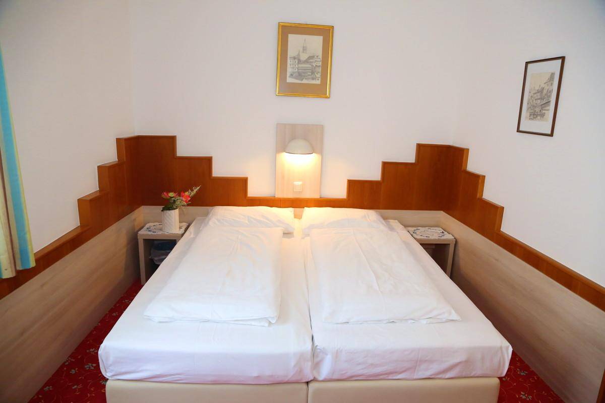 Schlafzimmer mit Doppelbett, Holzelementen und rotem Teppichboden.