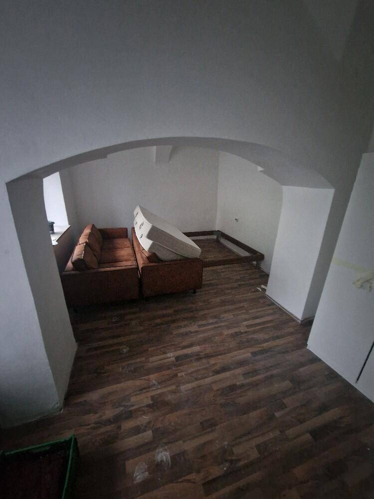 Großer Raum mit Holzboden und gewölbter Decke, ideal für ein Wohnzimmer.