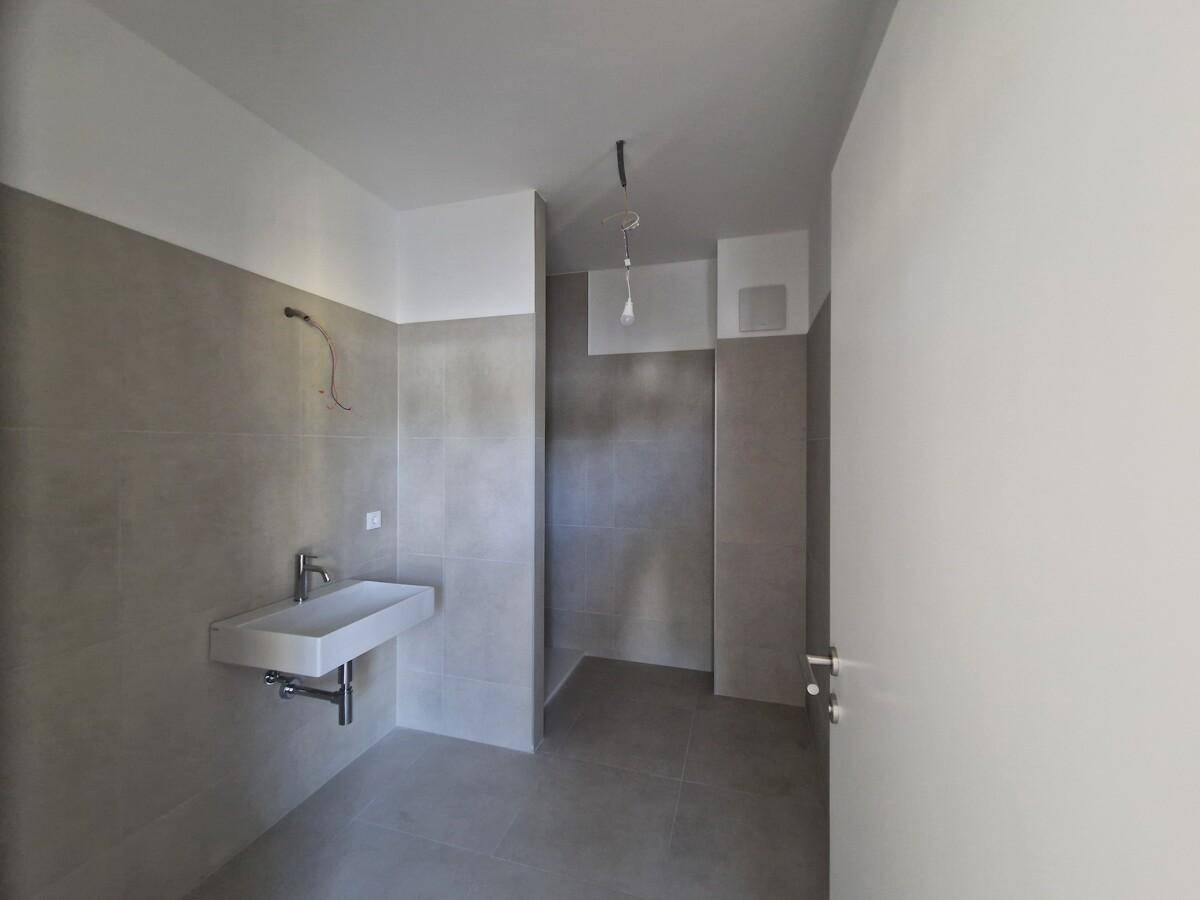 Helles Badezimmer mit schwebendem Waschbecken und begehbarer Dusche.
