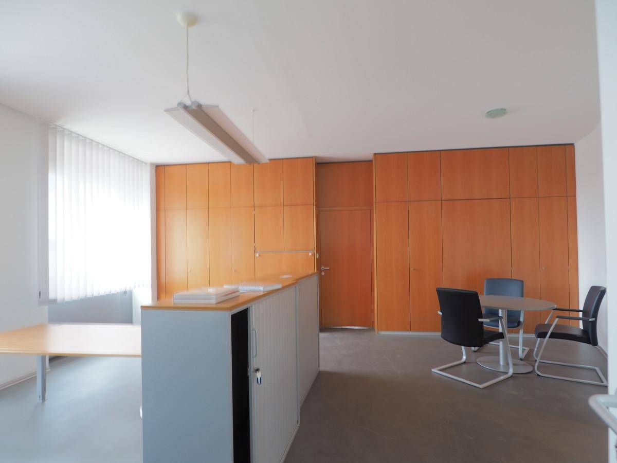 Heller Büroraum mit umfangreichen Holzschränken, einem Tisch und Stühlen für Besprechungen.