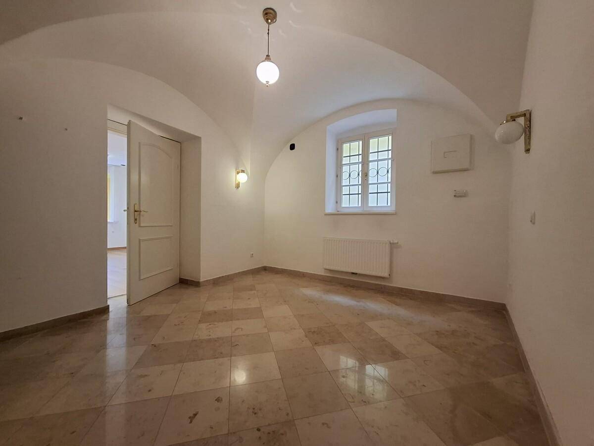 Wohnraum mit Gewölbedecke, Marmorboden und einem Fenster mit Gitter, das viel Licht hereinlässt.