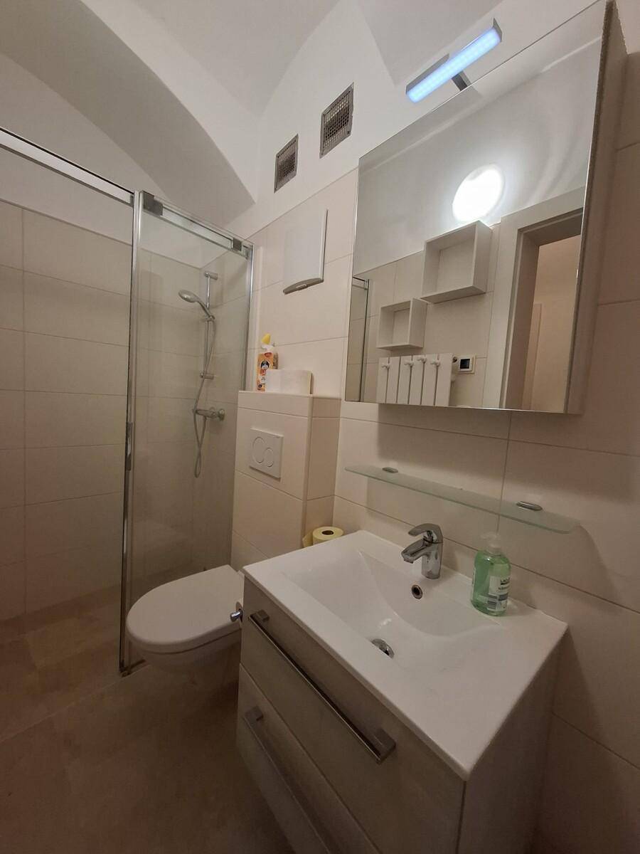 Modernes Badezimmer mit Dusche, WC und Waschbecken, ausgestattet mit hellen Fliesen.