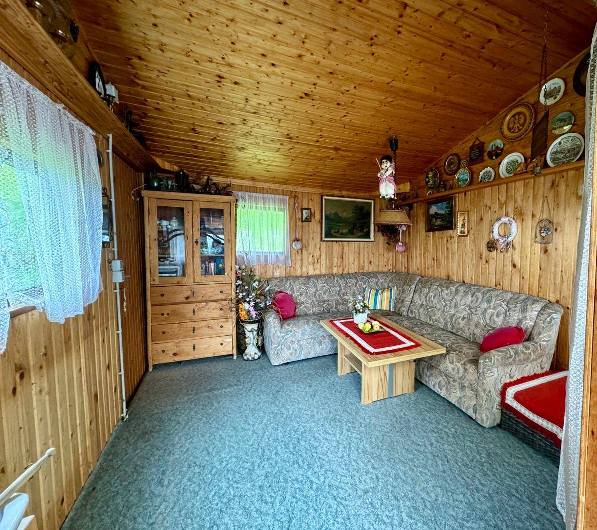 Rustikaler Wohnraum mit Holzvertäfelung an Wänden und Decke sowie Teppichboden.