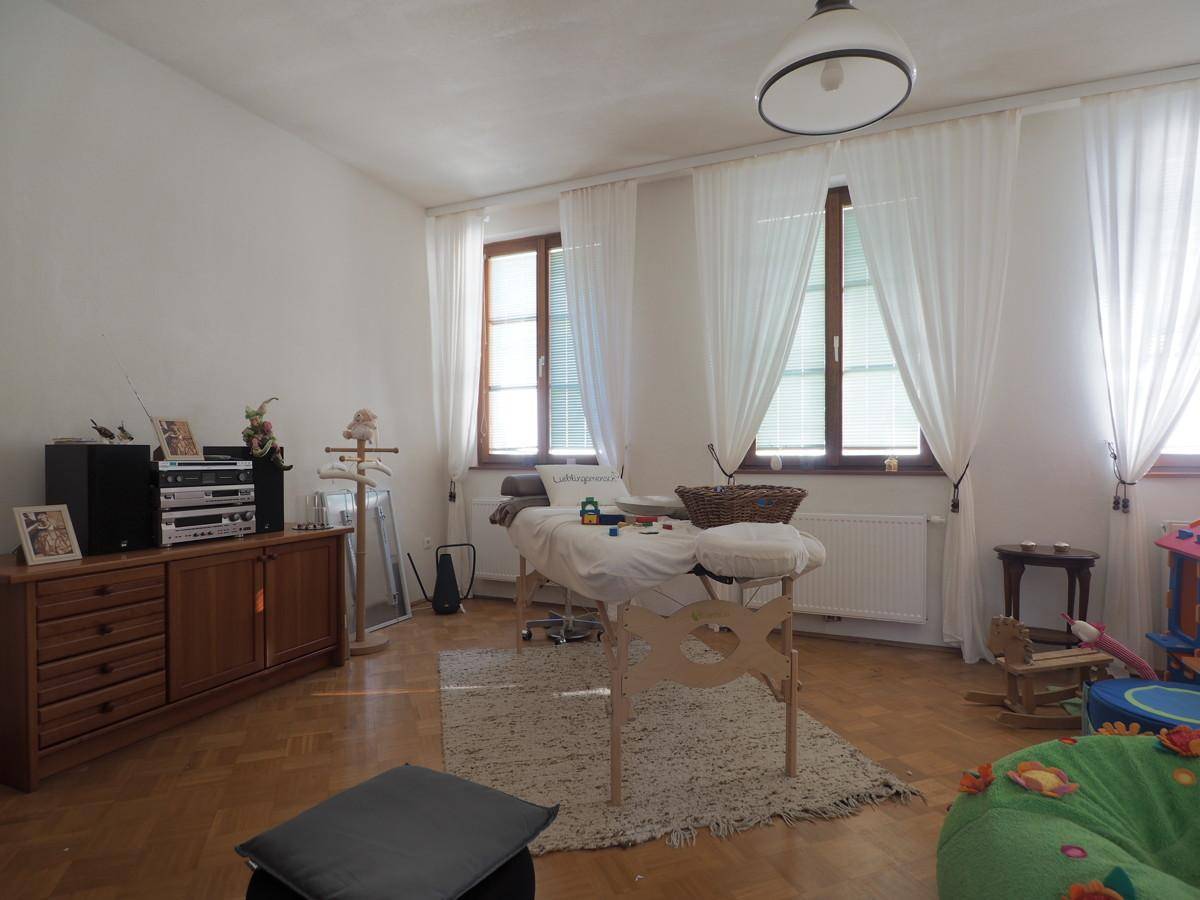Heller Raum mit Holzboden, großen Fenstern und vielseitiger Nutzung als Therapie- oder Spielzimmer.