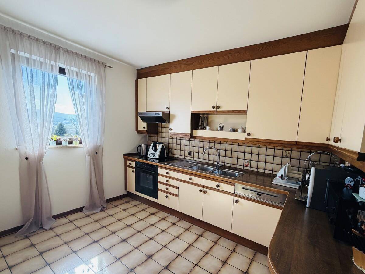 Traditionelle Küche mit Fliesenboden, Einbaugeräten und Fenster mit Ausblick.