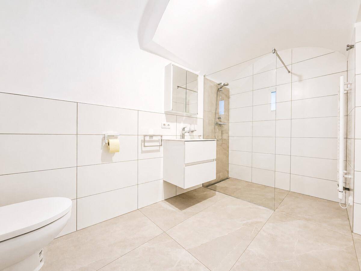 Modernes Badezimmer mit begehbarer Dusche, wandhängendem WC und eleganten Fliesen.