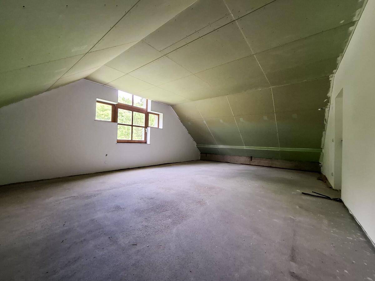 Großer, unausgebauter Dachraum mit schrägen Wänden und Fenstern, ideal für zukünftige Gestaltung.