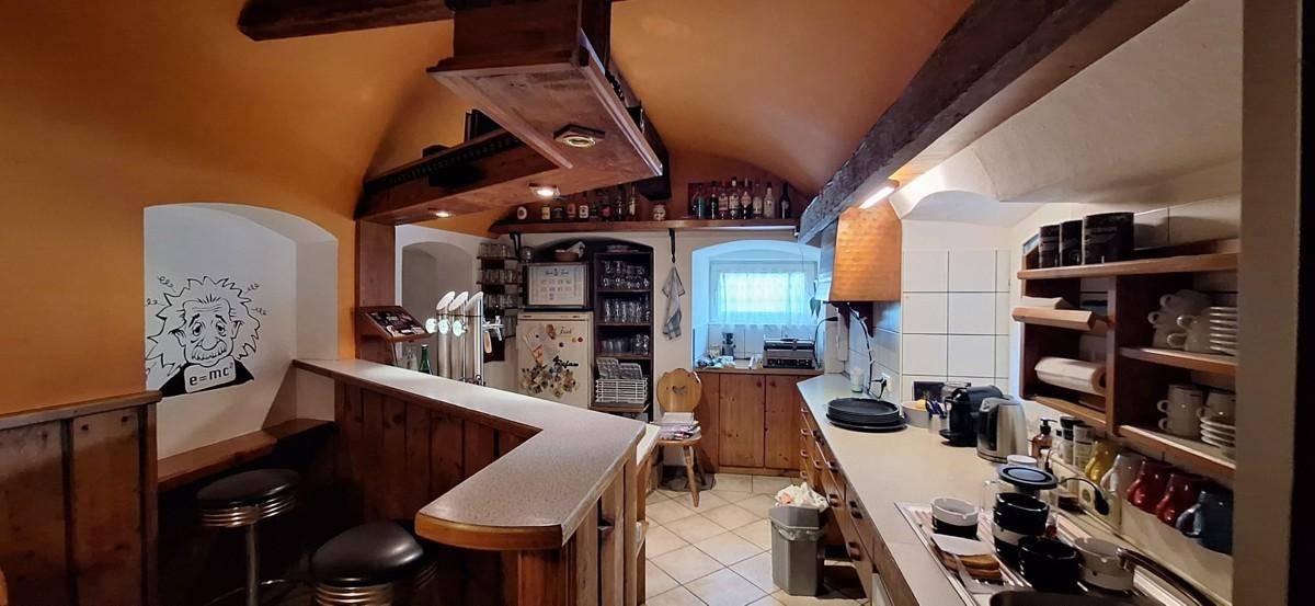 Professionelle Küche und Bar mit Holzbalken, Fliesenboden und umfangreicher Ausstattung.
