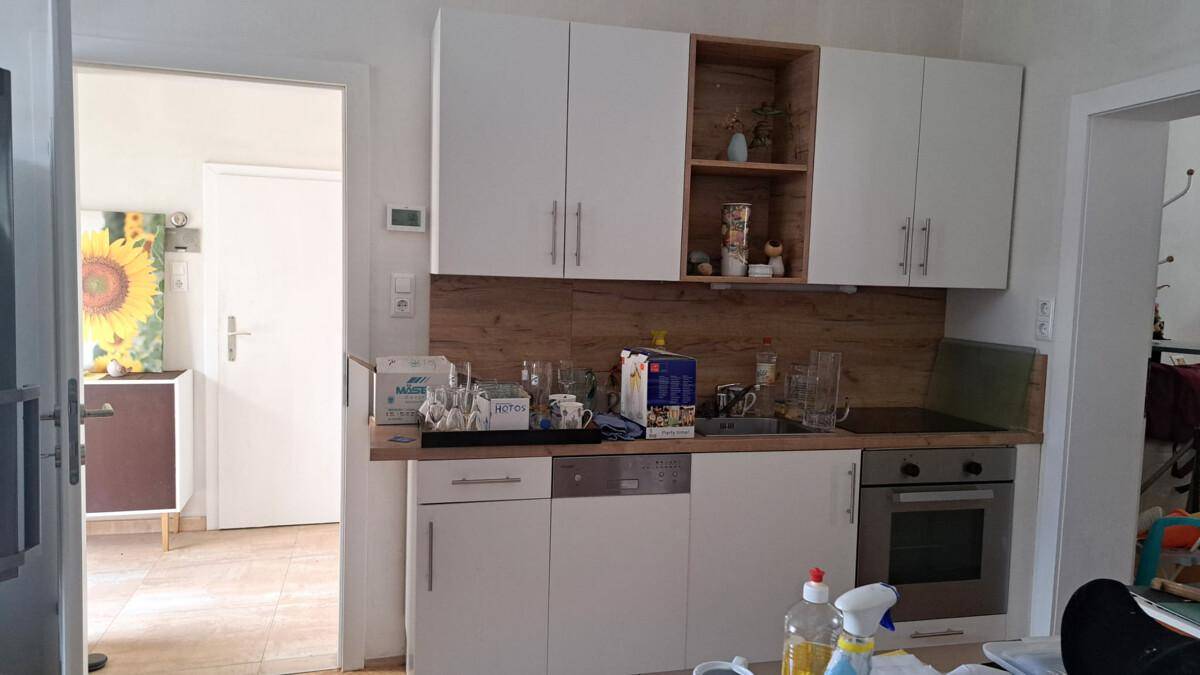 Moderne Küche mit weißen Schränken, Holzakzenten und integrierten Geräten.