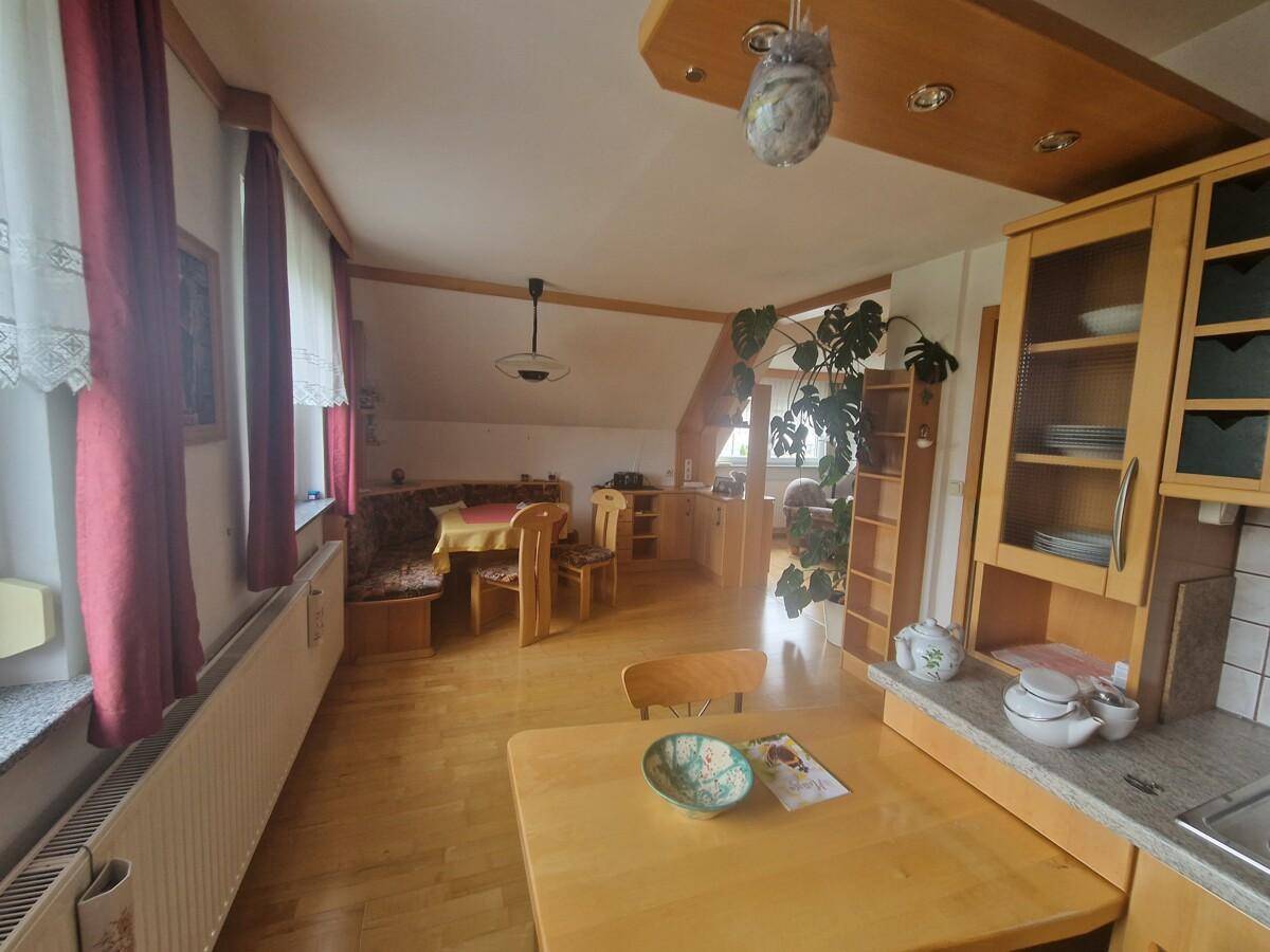 Offener Wohn- und Essbereich mit Holzmöbeln, Parkettboden und Blick in den angrenzenden Raum.