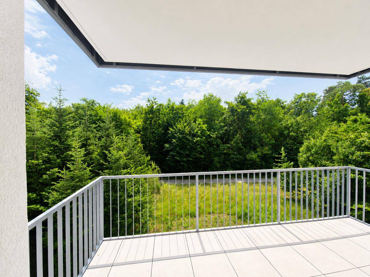 Geräumiger Balkon mit Fliesenboden und unverbautem Blick auf die umliegende Natur.