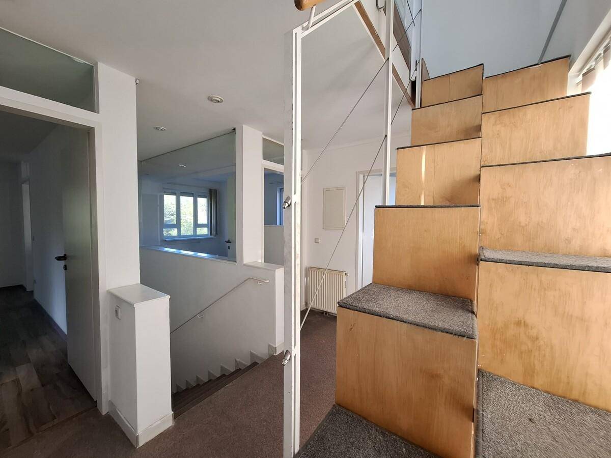 Heller Flur mit Treppe und moderner Glasbrüstung, die viel Licht durchlässt.