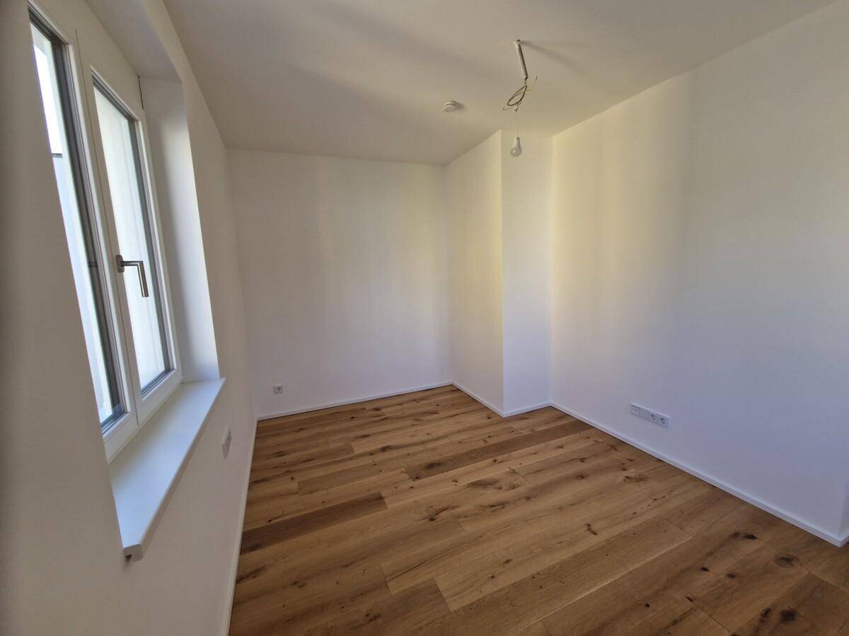 Helles Schlafzimmer mit großen Fenstern und hochwertigem Parkettboden.