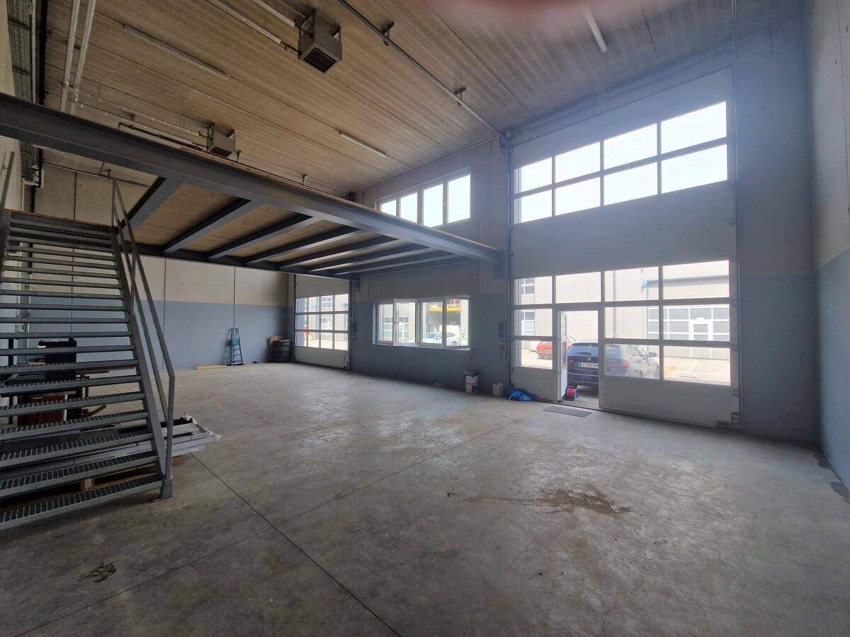 Weitläufiger Industrieraum mit Betonboden, hohen Decken und mehreren großen Rolltoren.