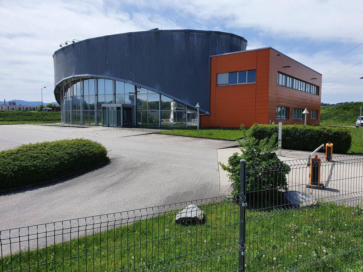 Moderne Bürogebäude-Architektur mit geschwungener Glasfassade und orangefarbenen Akzenten unter blauem Himmel.