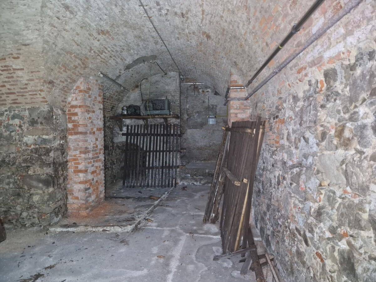 Historischer Keller mit unverputzten Steinwänden, Ziegelgewölbe und Lagerbereich.