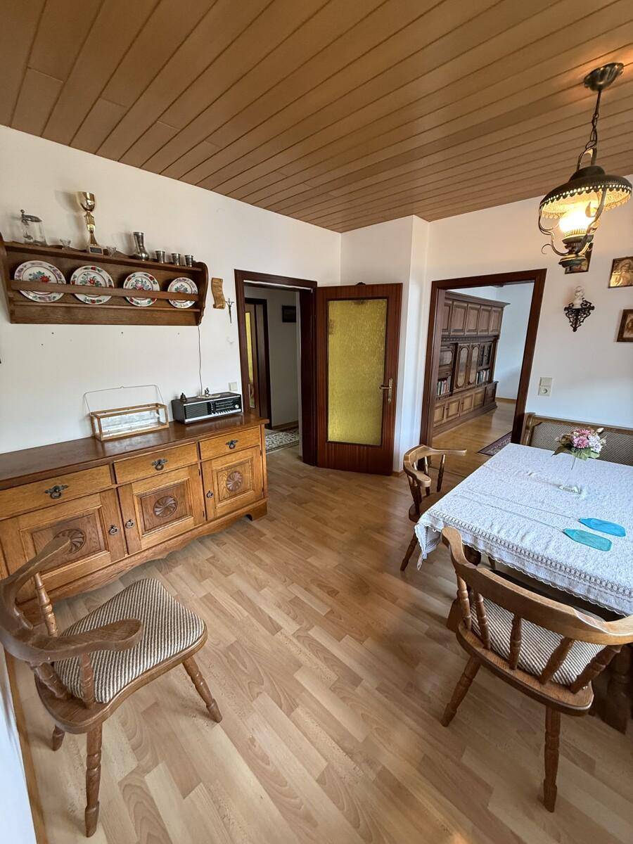 Essbereich mit Holztisch, Stühlen und traditionellen Möbeln in warmen Tönen.