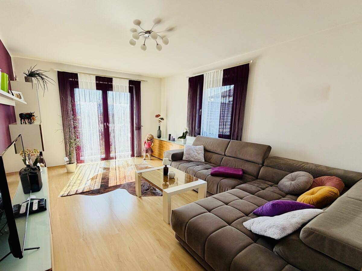 Helles Wohnzimmer mit bequemer Eckcouch, Parkettboden und Zugang zum Außenbereich.