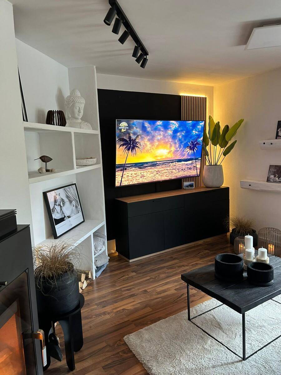 Helles Wohnzimmer mit modernem Dekor, großem Fernseher und gemütlicher Atmosphäre.