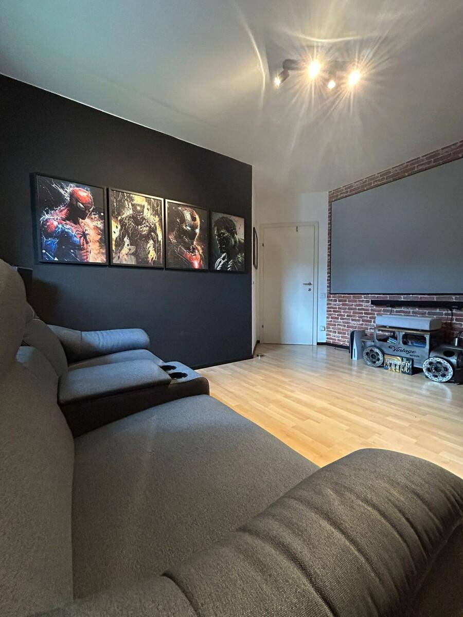 Heimkino mit großer Leinwand, bequemen Sofas und dunkler Wandgestaltung für Filmerlebnisse.