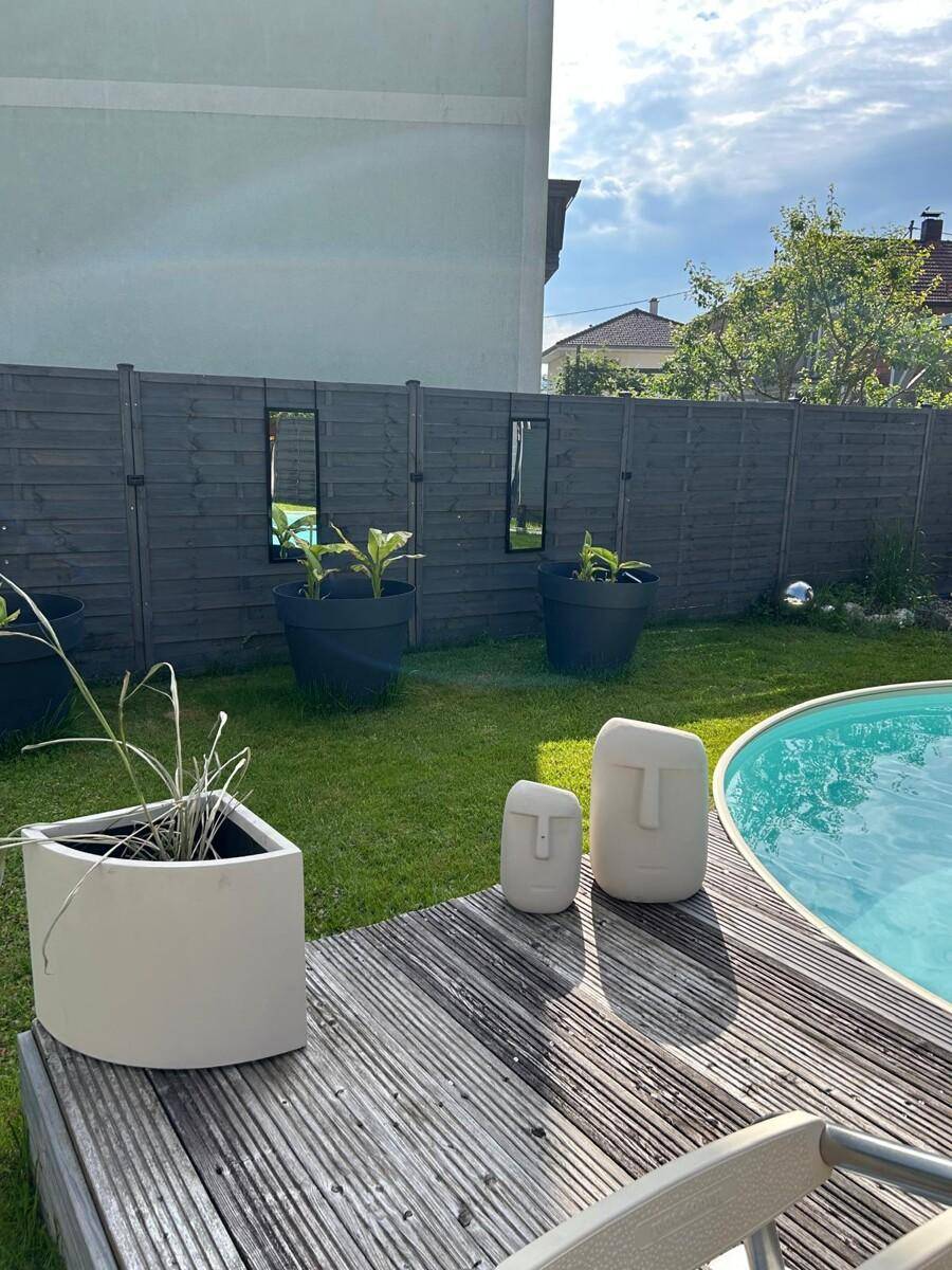 Poolbereich im Garten mit Holzdeck, dekorativen Pflanzgefäßen und einem oberirdischen Pool.