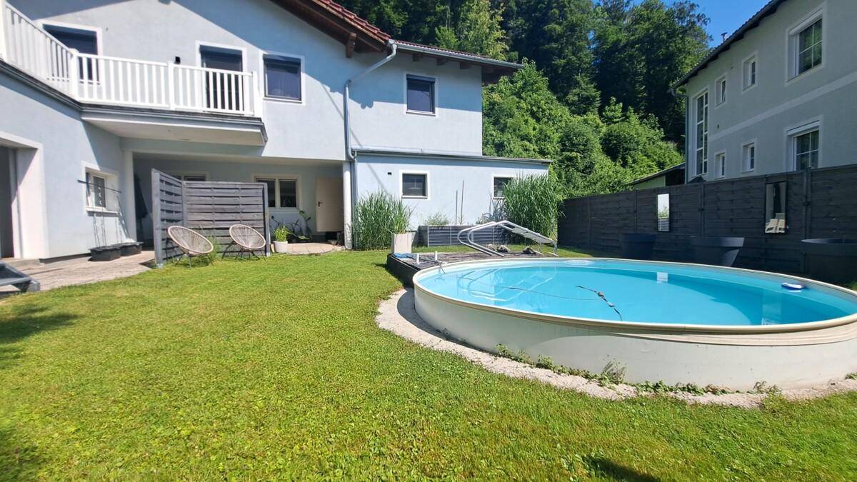 Hinteransicht des Hauses mit großem Garten, oberirdischem Pool und angrenzender Terrasse.