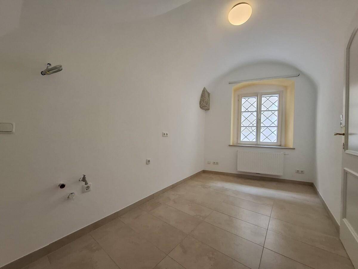 Helles Zimmer mit Gewölbedecke, Fliesenboden und Fenster, ideal als Schlafzimmer.