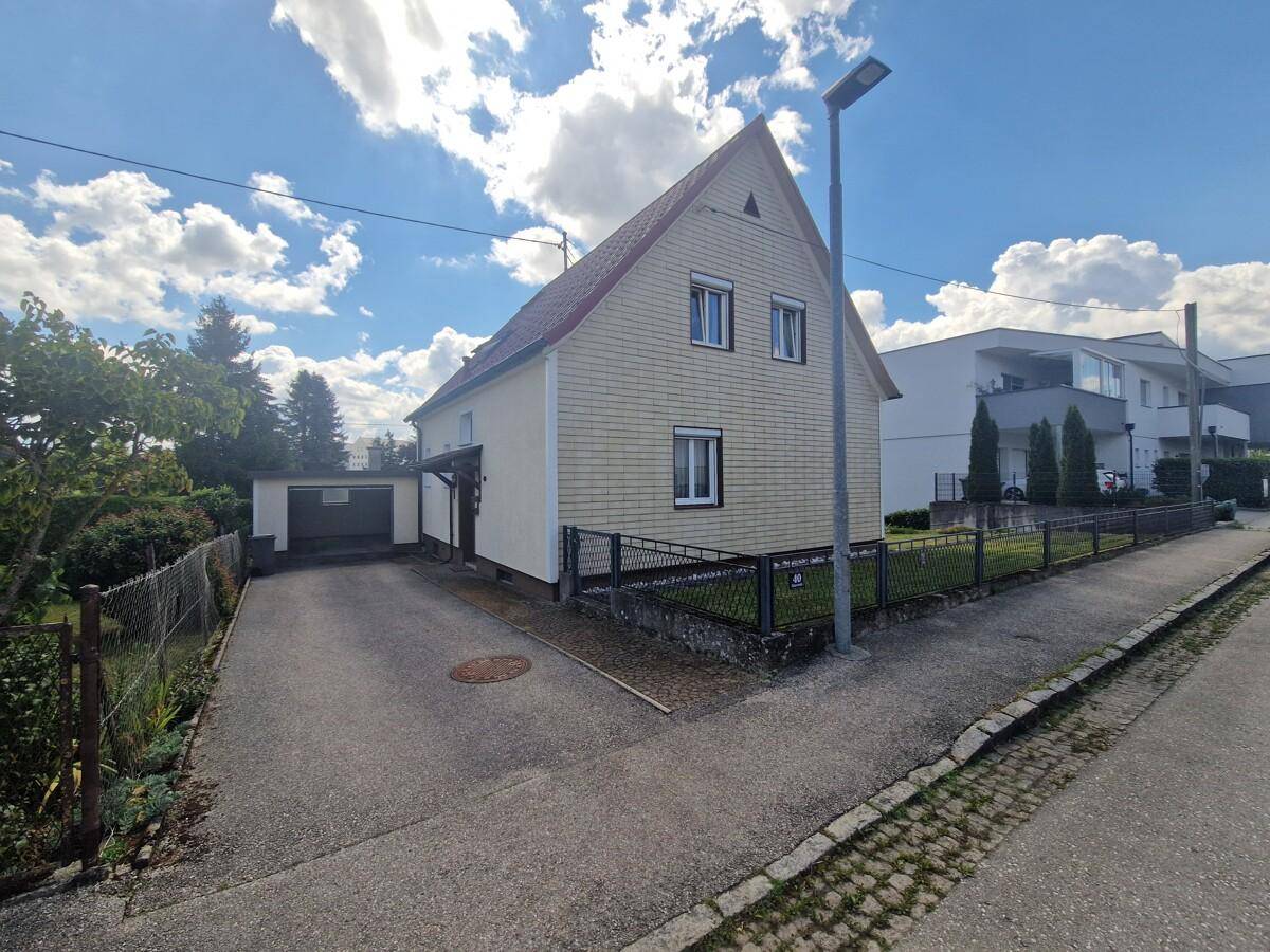Seitenansicht des Hauses mit Einfahrt zur Garage und gepflegtem Vorgarten.
