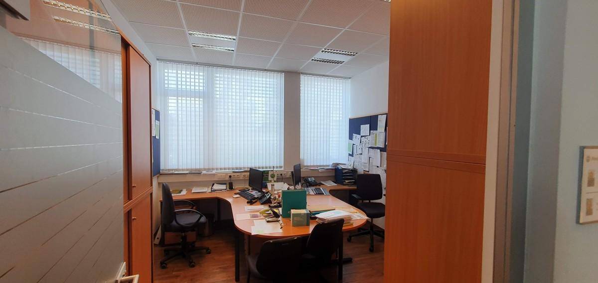 Helles Einzelbüro mit großem Fenster, Holzboden und einem Schreibtisch mit Bürostuhl für konzentriertes Arbeiten.