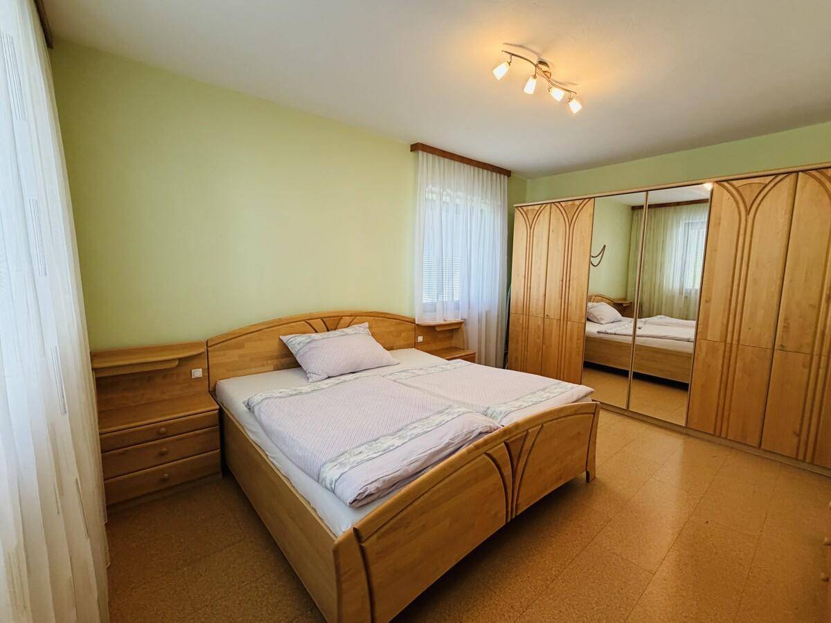 Helles Schlafzimmer mit Doppelbett, Einbauschränken und grün gestrichenen Wänden.