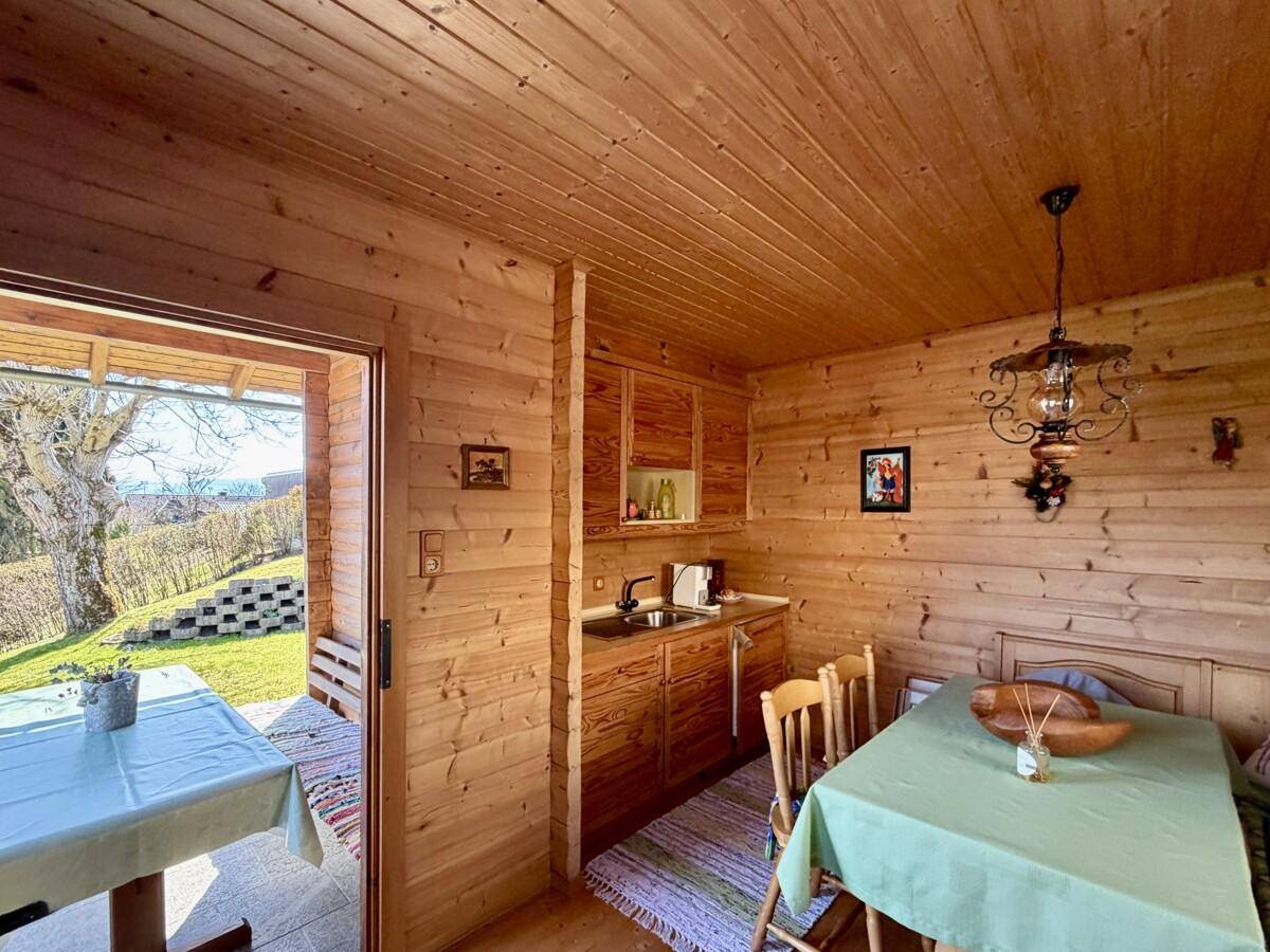 Gemütliche Küchenzeile im Gartenhaus mit Holzwänden und Essbereich im Landhausstil.