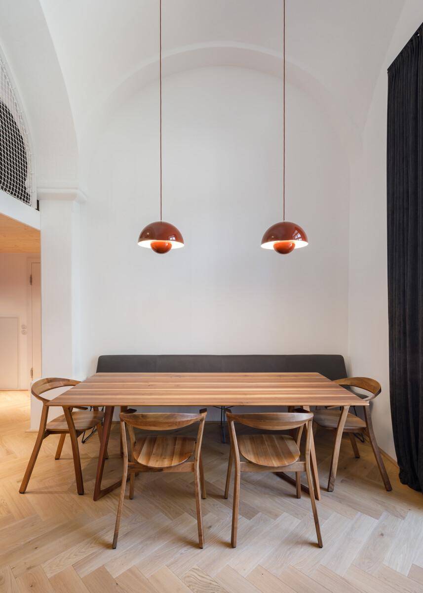 Essbereich mit Holztisch, modernen Stühlen und zwei Hängelampen unter hoher Decke.