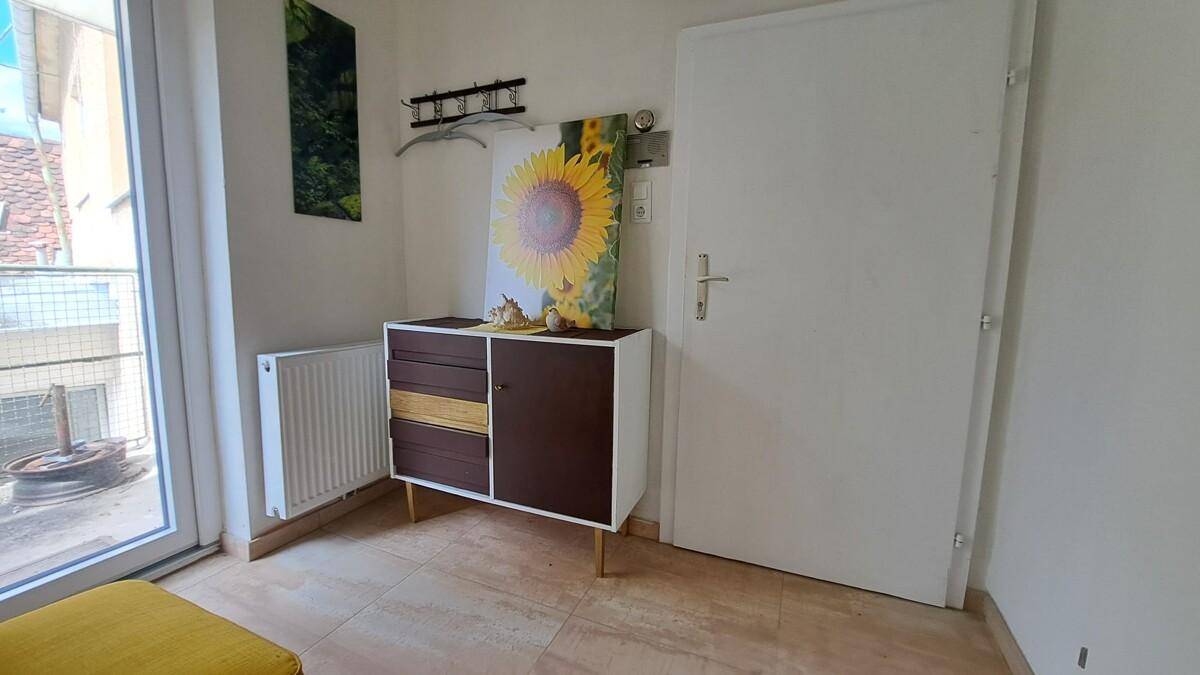 Eingangsbereich mit Kommode, Garderobe und Zugang zu einem Balkon oder einer Terrasse.