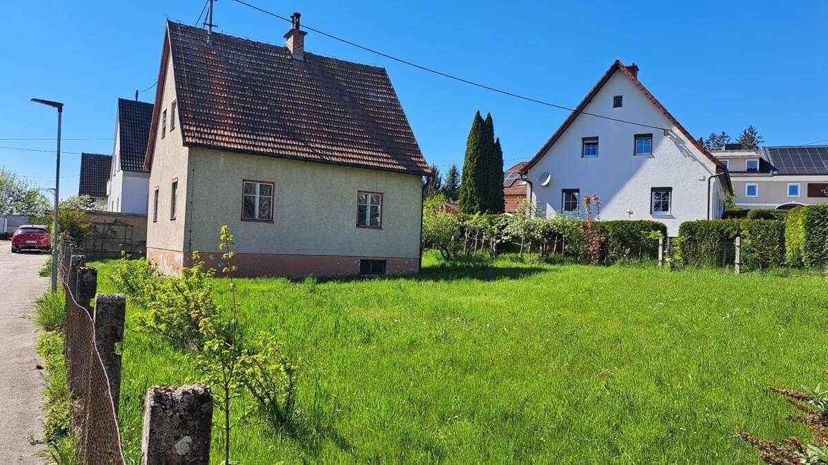 Freistehendes Haus mit großem Rasengrundstück und Blick auf Nachbargebäude.