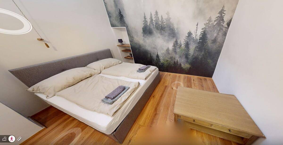 Schlafzimmer mit Doppelbett, Holzboden und einer Akzentwand mit Waldmotiv.