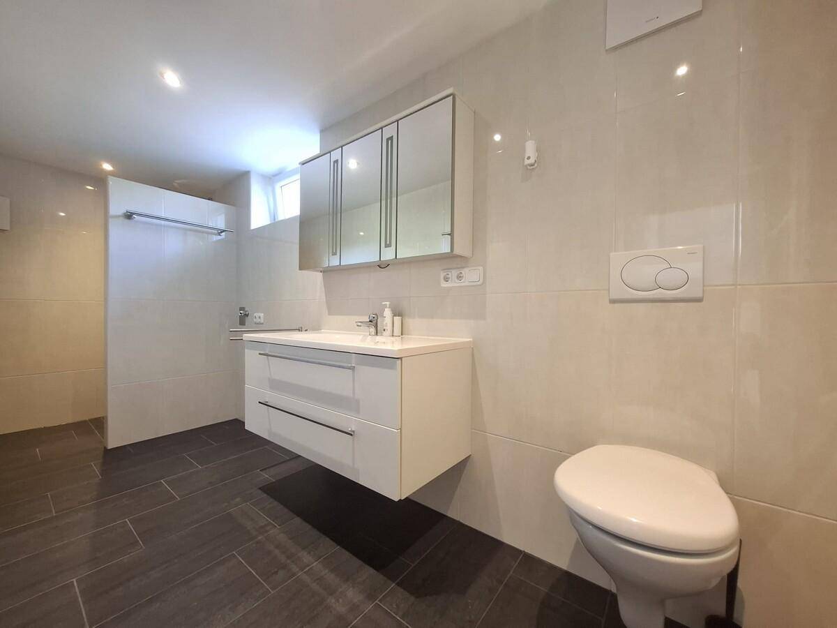 Modernes Badezimmer mit dunklen Fliesen, Waschtisch und wandhängendem WC.
