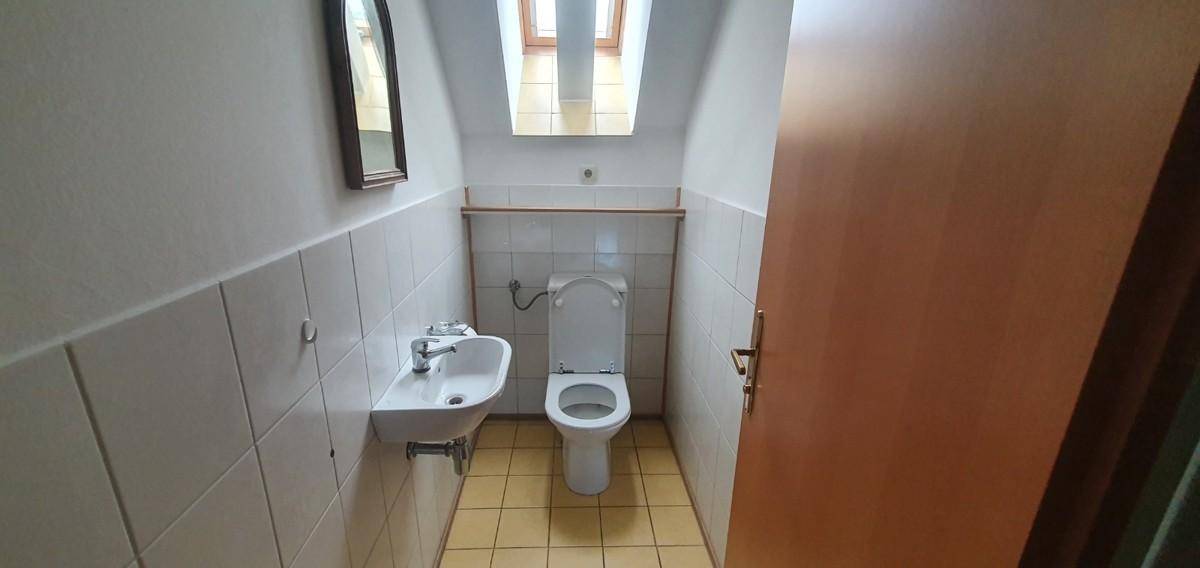 Kleines Gäste-WC mit Fliesenboden, Waschbecken und Dachfenster für Tageslicht.
