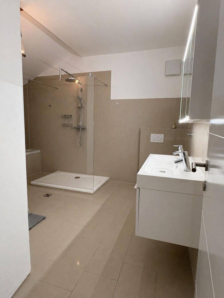 Modernes Badezimmer mit begehbarer Dusche, Doppelwaschbecken und hellen Fliesen.